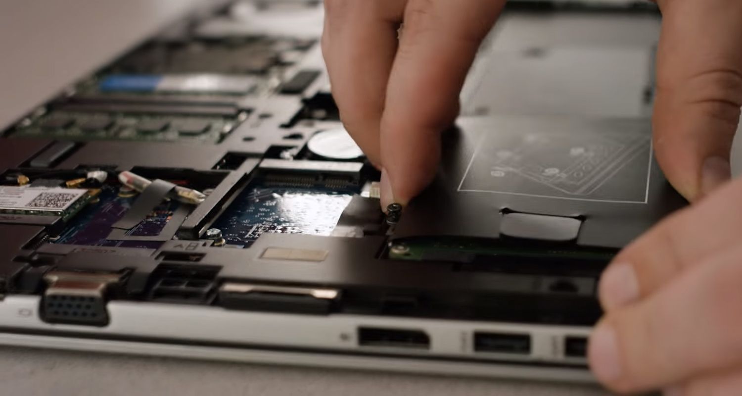 SSD Crucial sendo fixado no compartimento de armazenamento de um notebook