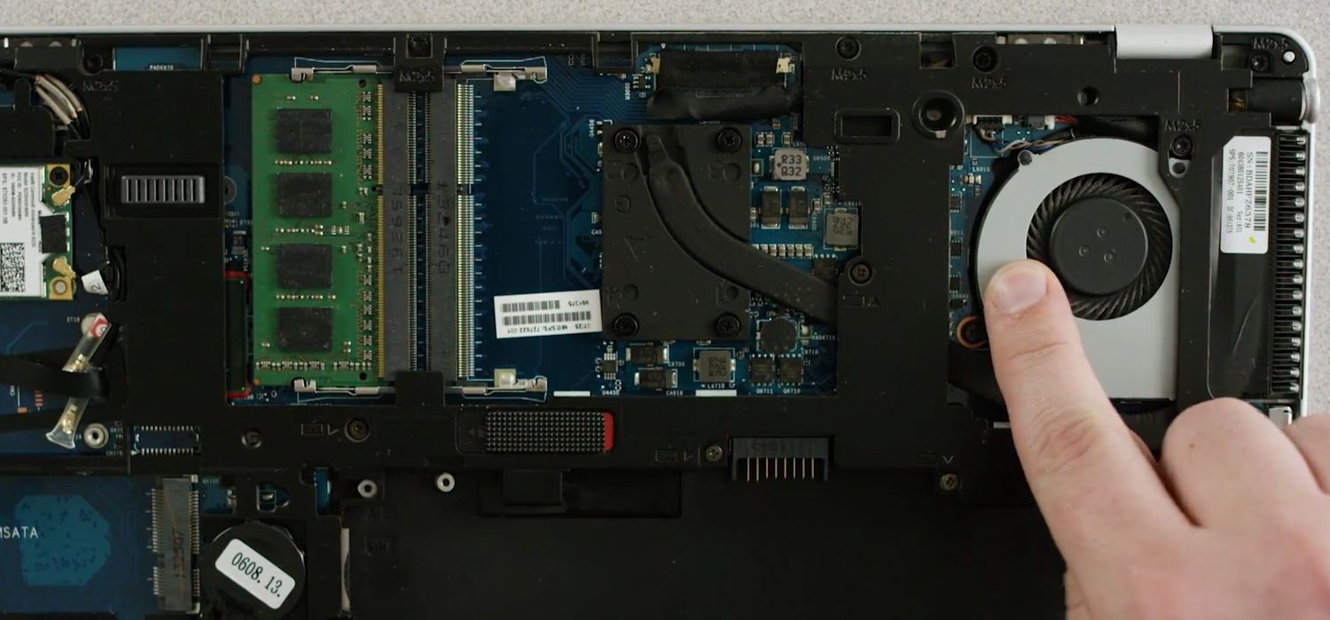 Dedo de uma pessoa tocando a superfície metálica sem pintura na parte inferior exposta de um laptop para descarregar a eletricidade estática.